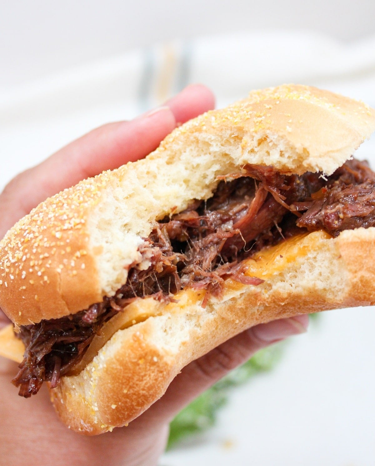 slow cooker hot beef sandwich held in hand with bite taken