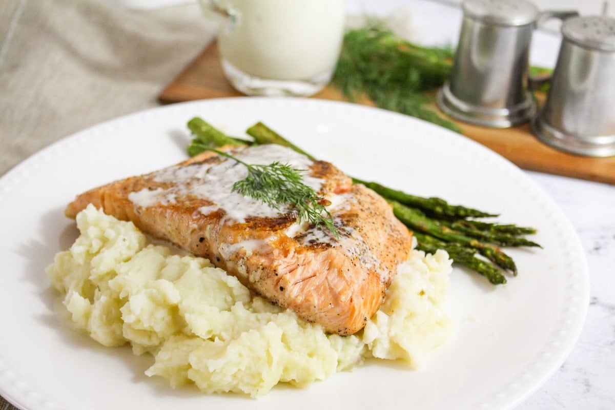 plated salmon with champagne sauce and dill on topand mashed potatoes