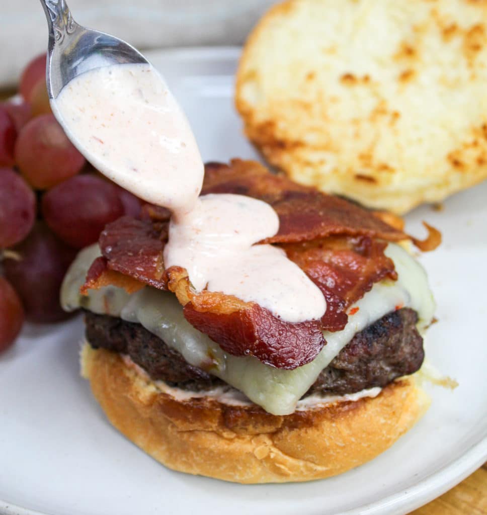 burger on a plate with sauce spooned on top