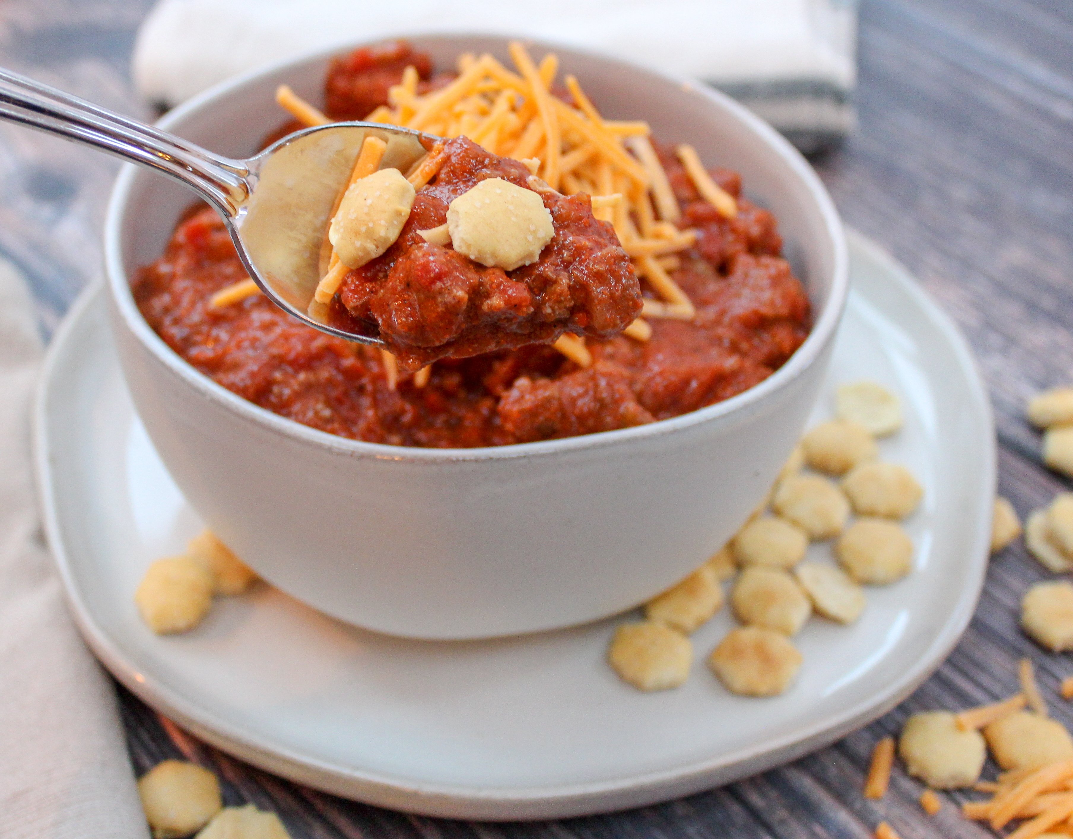 White bowl filled with chili and topped with cheese