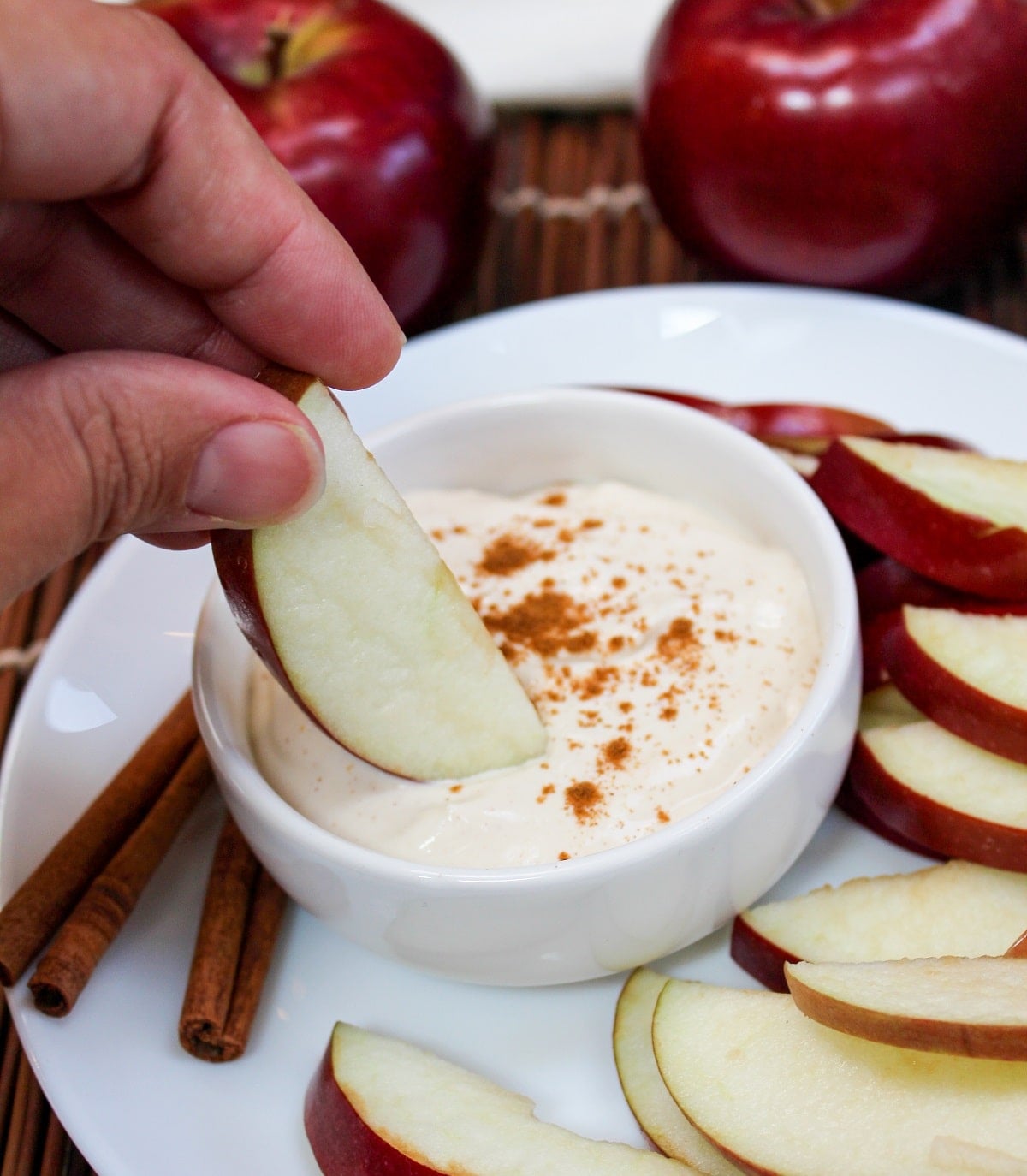 apple cider dip in a bowl with sliced apples and an apple dipped into the dip