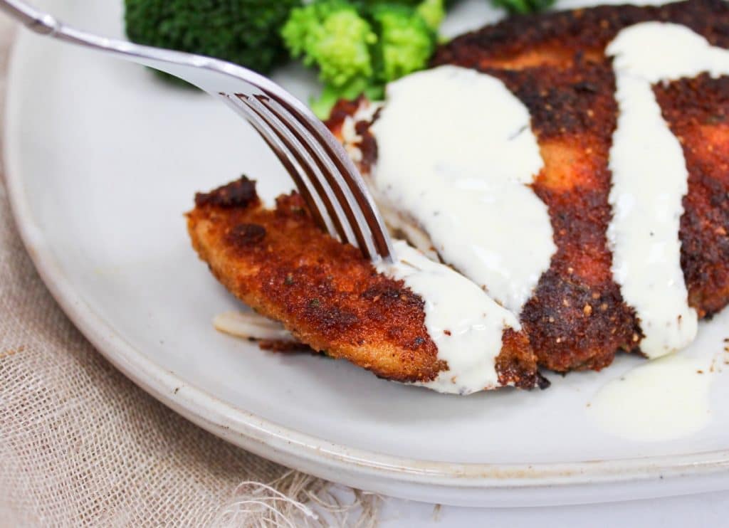 Crispy Parmesan Chicken with Lemon Hollandaise sliced on a fork with sauce