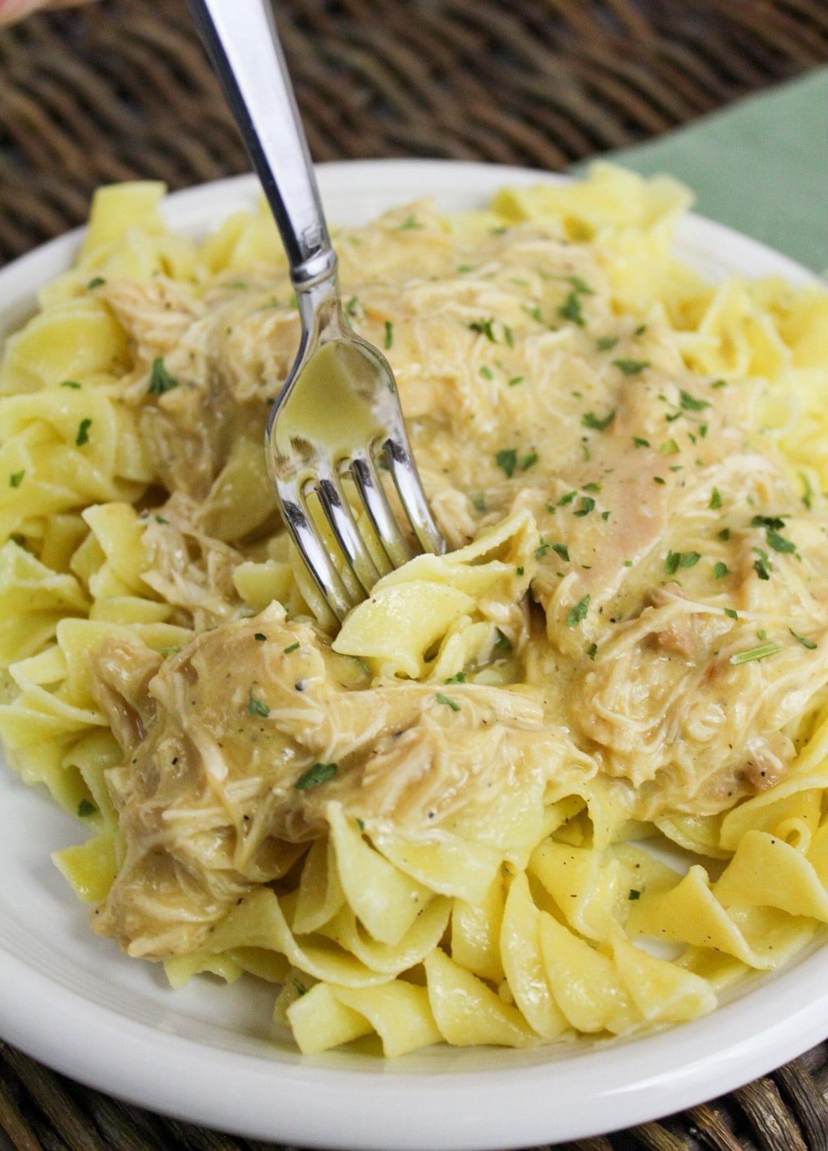 slow cooker italian chicken over noodles on a fork