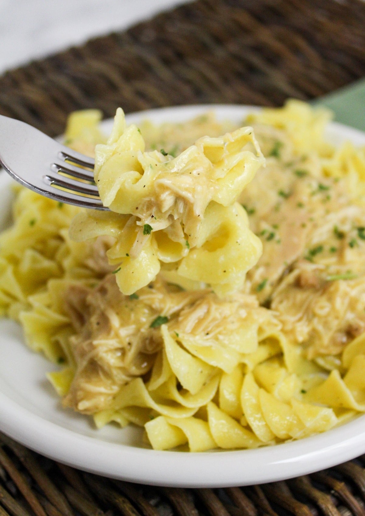slow cooker italian chicken over noodles on a fork