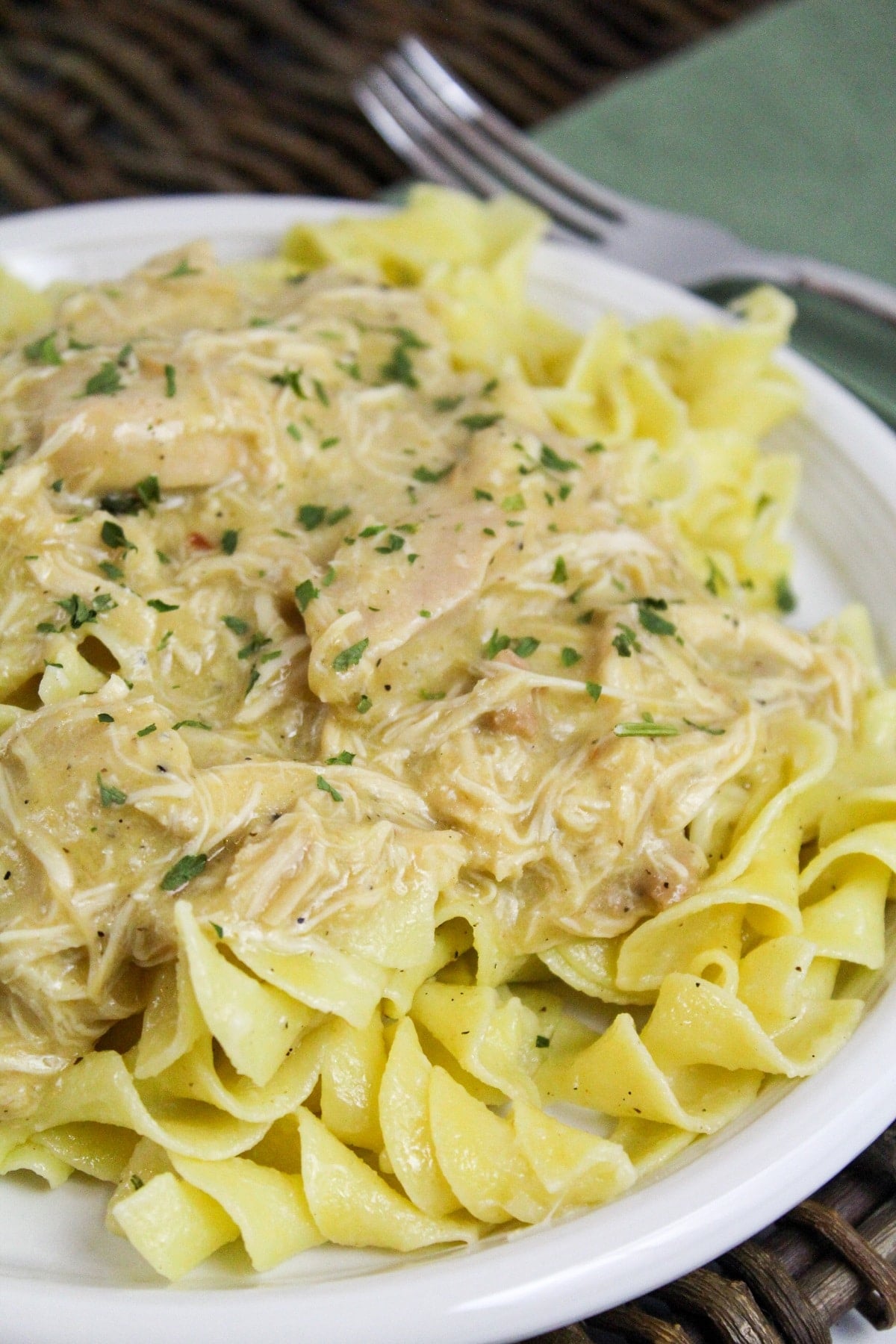 slow cooker italian chicken over noodles on a white plate