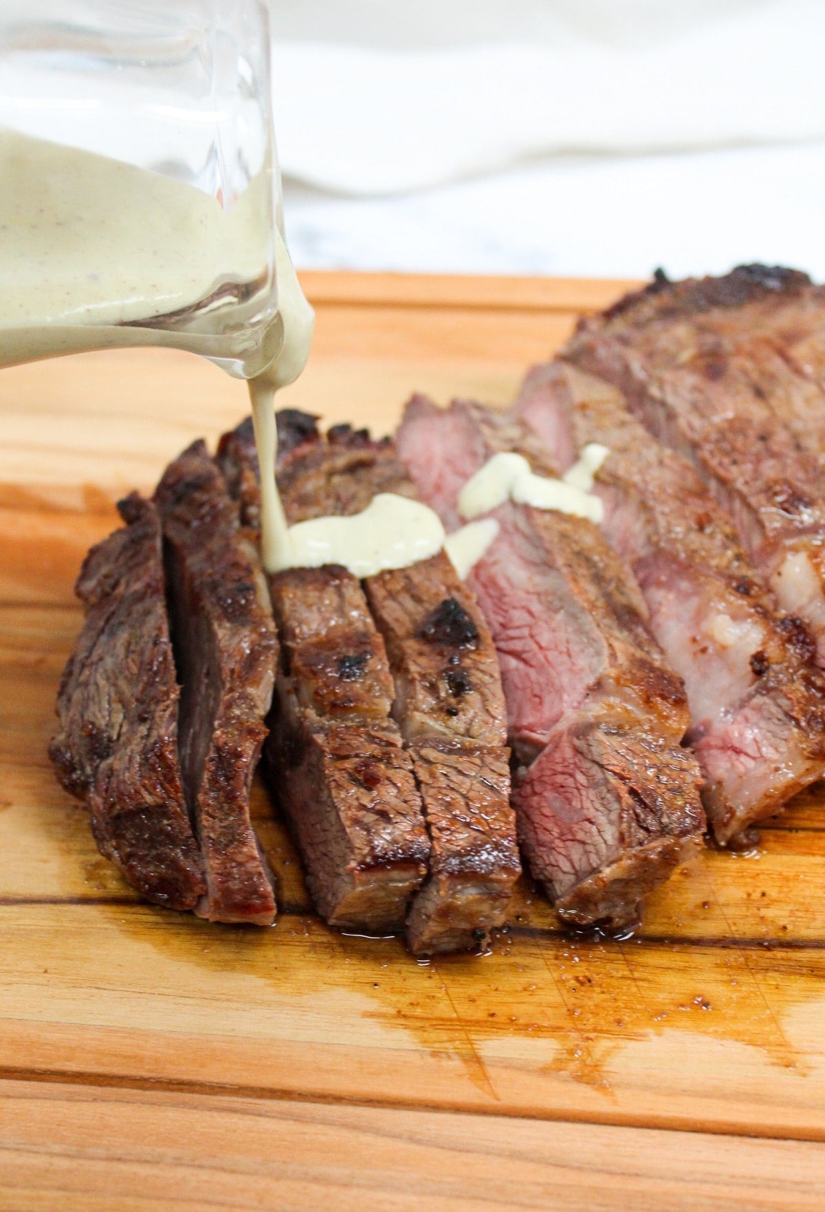 Grilled Ribeye with Garlic Blue Cheese Mustard Sauce on a cutting board and sliced with sauce on top