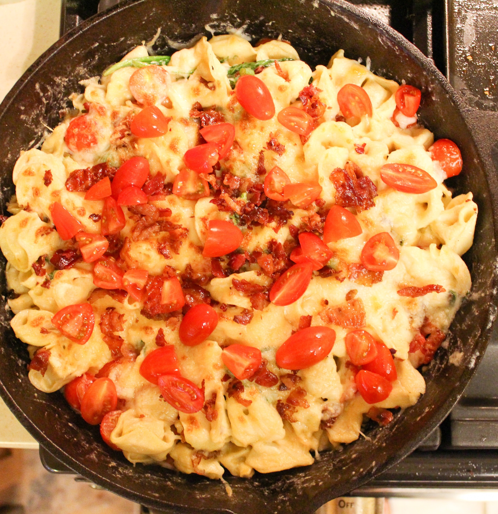 pasta in skillet topped with bacon and tomato