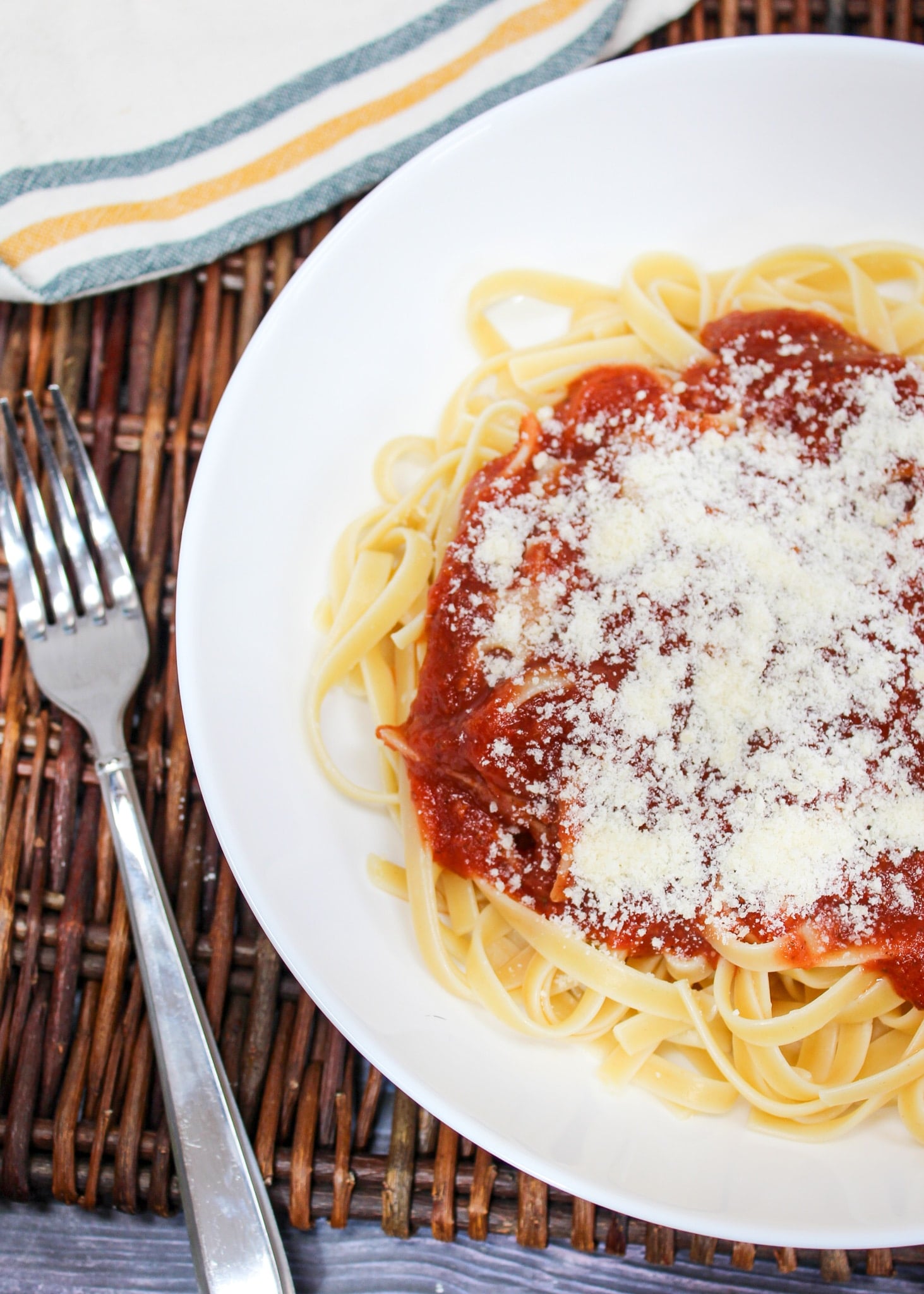 pasta sauce spooned over cooked pasta with parmesan cheese