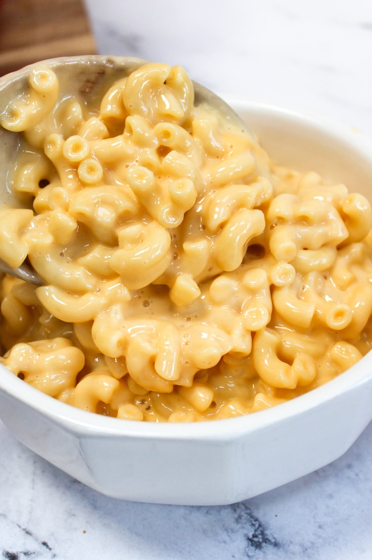 one-pot stove top mac and cheese put into a white bowl from a wooden spoon
