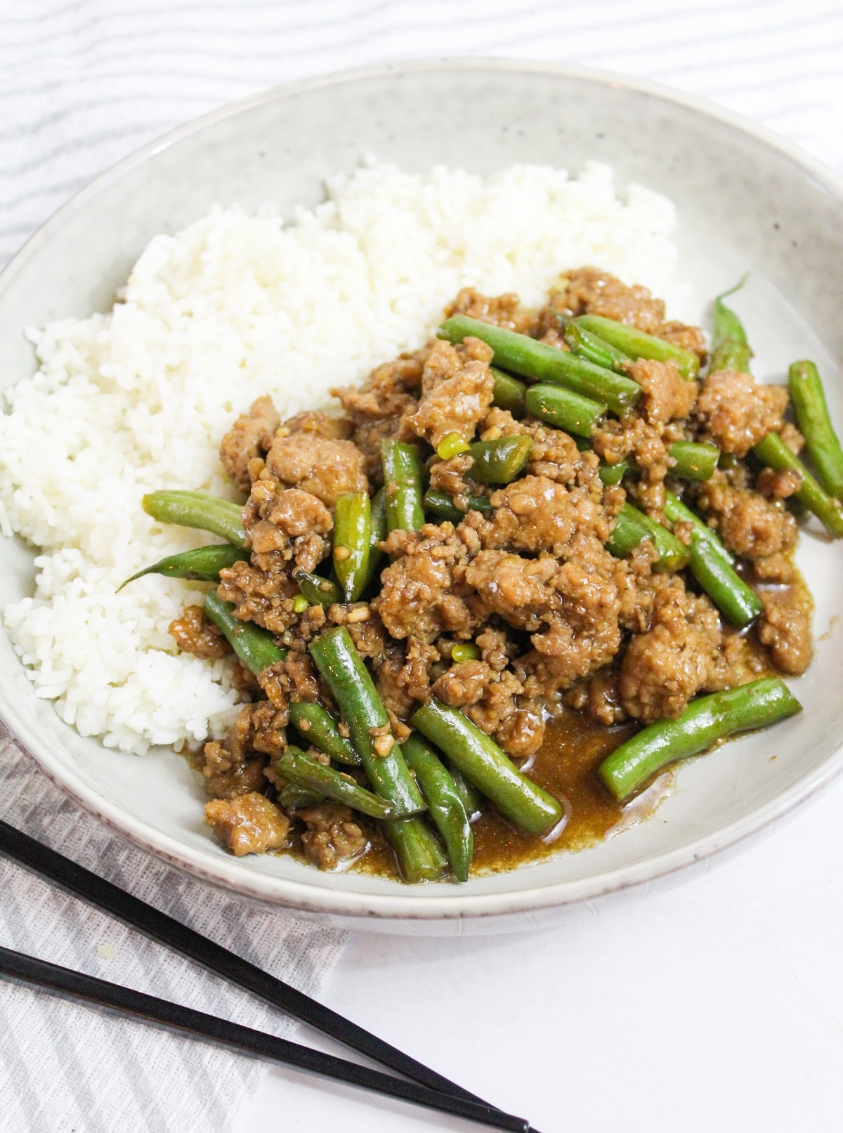 Szechuan Green Beans and Ground Pork in a white bowl with rice
