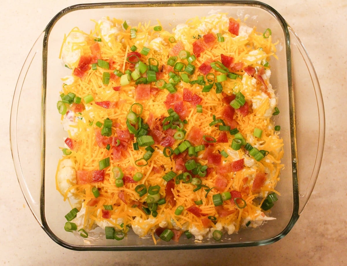 Casserole in a glass baking dish with bacon and onion