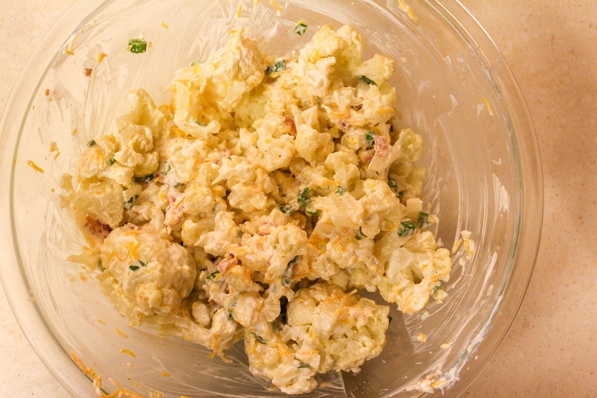 cauliflower with bacon, cheese, sour cream, and green onion mixed in a bowl