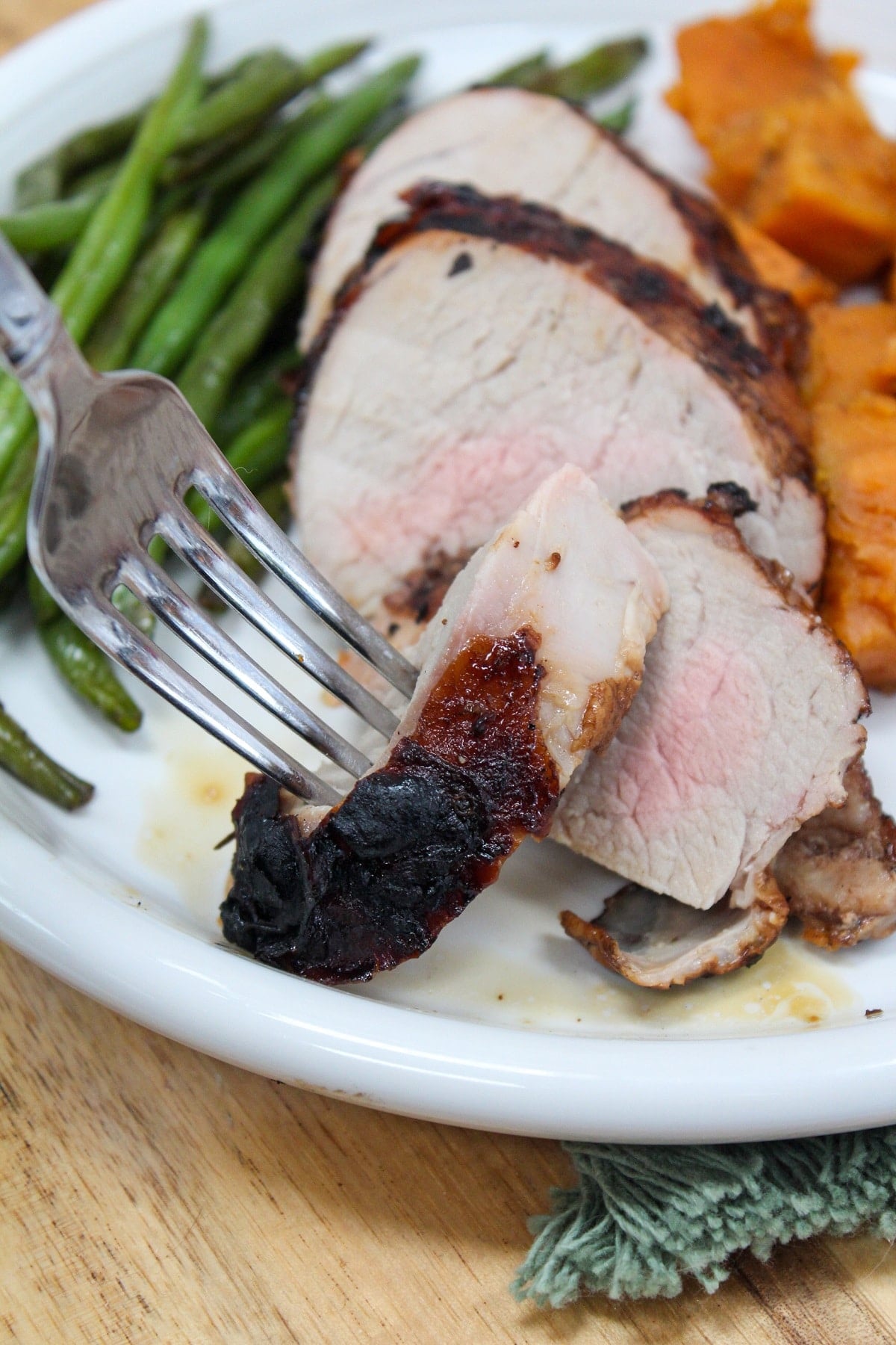 Grilled Honey Balsamic Pork Tenderloin grilled and sliced on a plate and sliced with sweet potatoes.