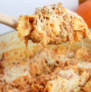 pasta scooped with a wooden spoon from a red pot