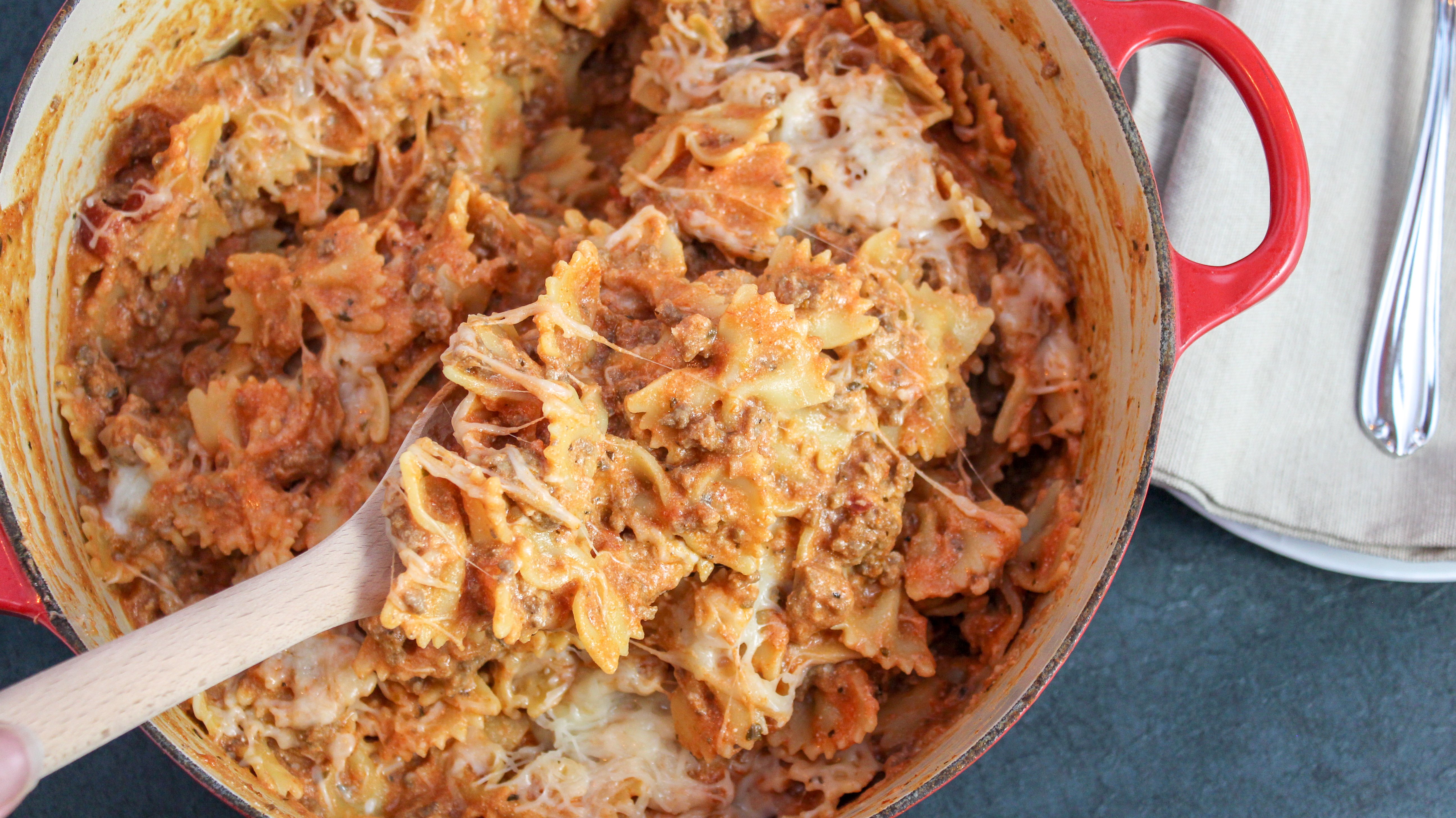 pasta scooped with a wooden spoon from a red pot
