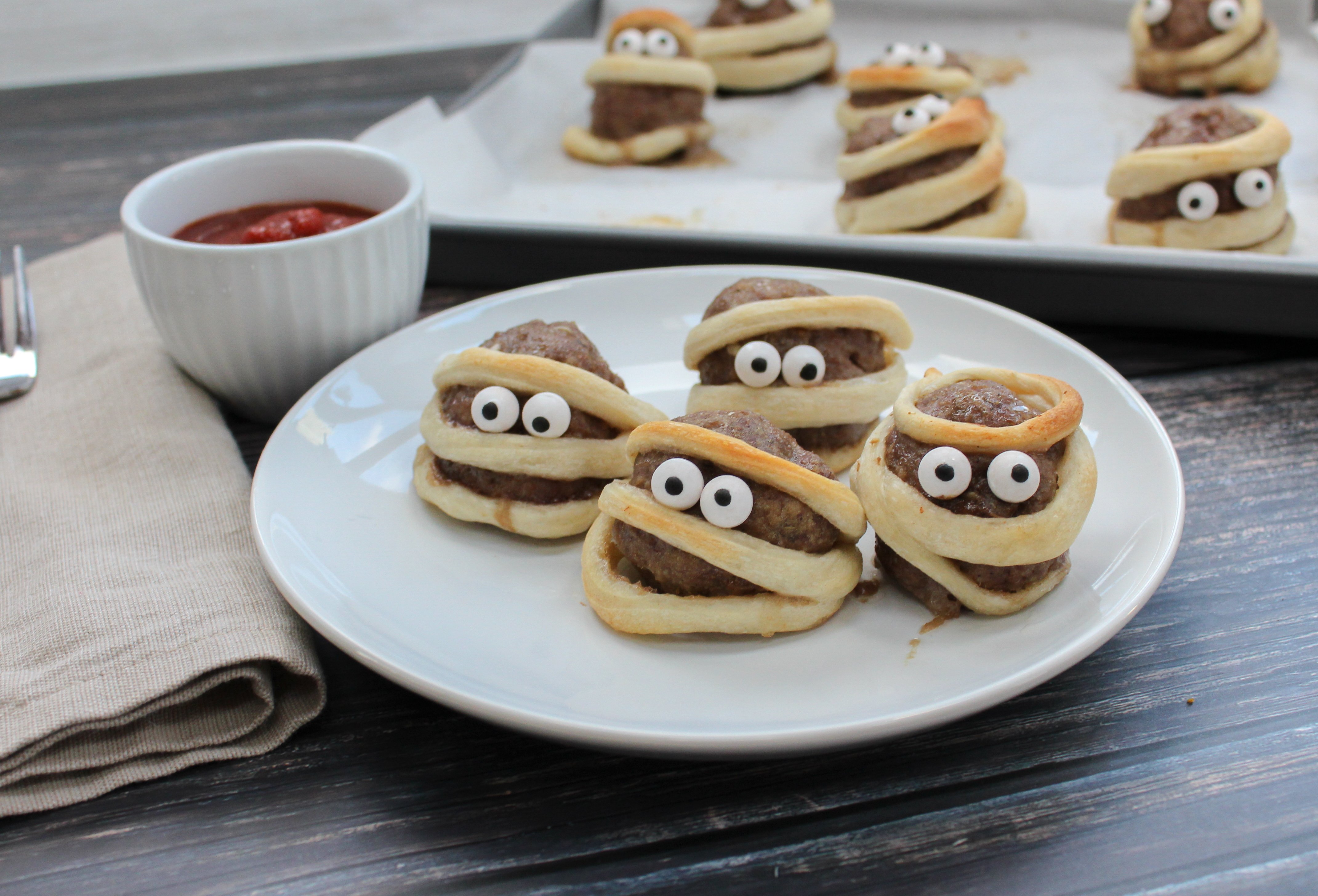 Meatballs wrapped in a strip of dough with candy eyes