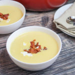 soup in white bowls topped with goast cheese crumbles and bacon