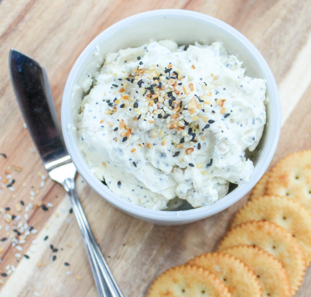 Spread in a white container wth crackers and a spreading knife