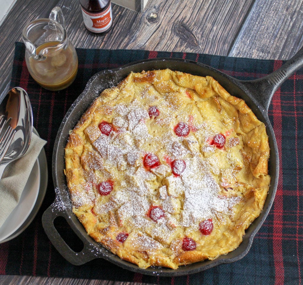 Bread pudding studded with cherries in a cast iron pan