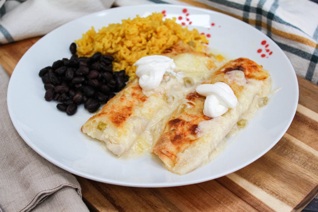 Chicken enchiladas on a plate with rice and beans