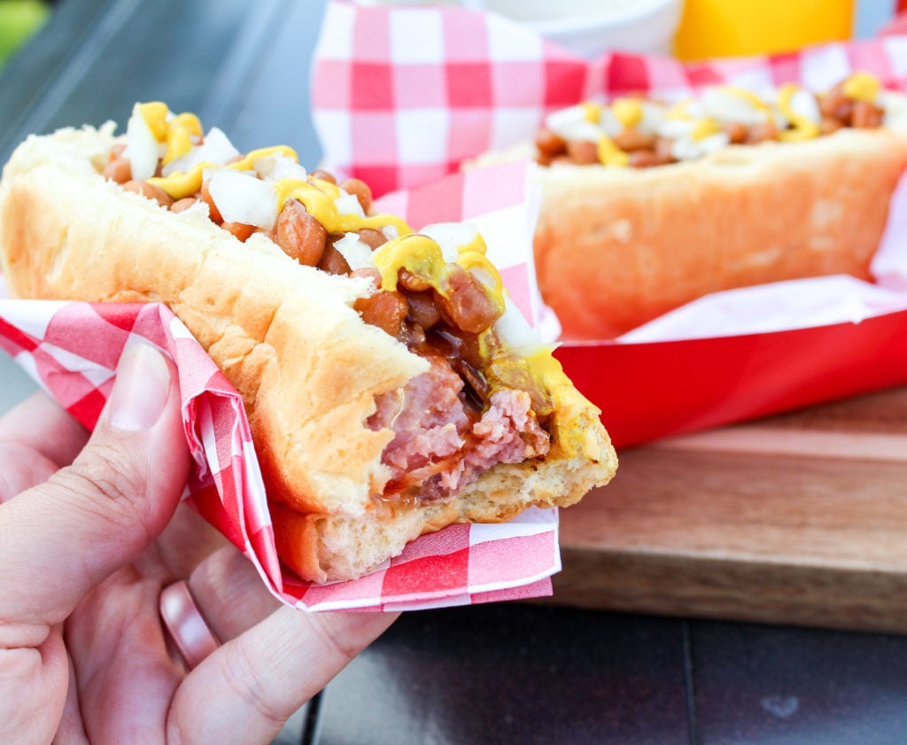 hot dog on the bun with beans and onion with a bite taken