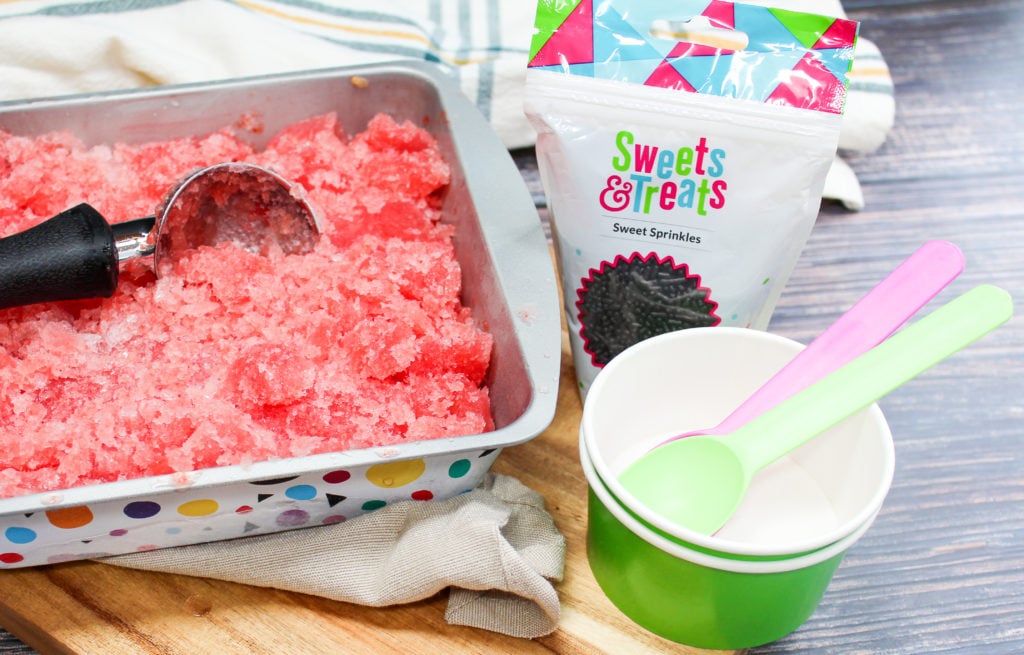 granita in a pan next to cups and spoon