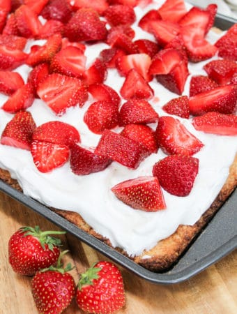 uncut photo of cake with whipped cream and strawberries