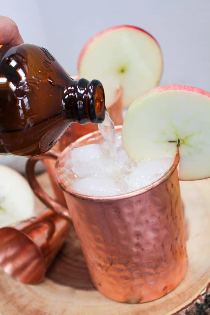 apple cider mule in a copper mug with an apple slice as a garnish