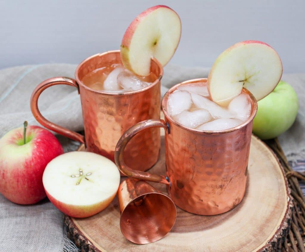apple cider mule in a copper mug with an apple slice as a garnish