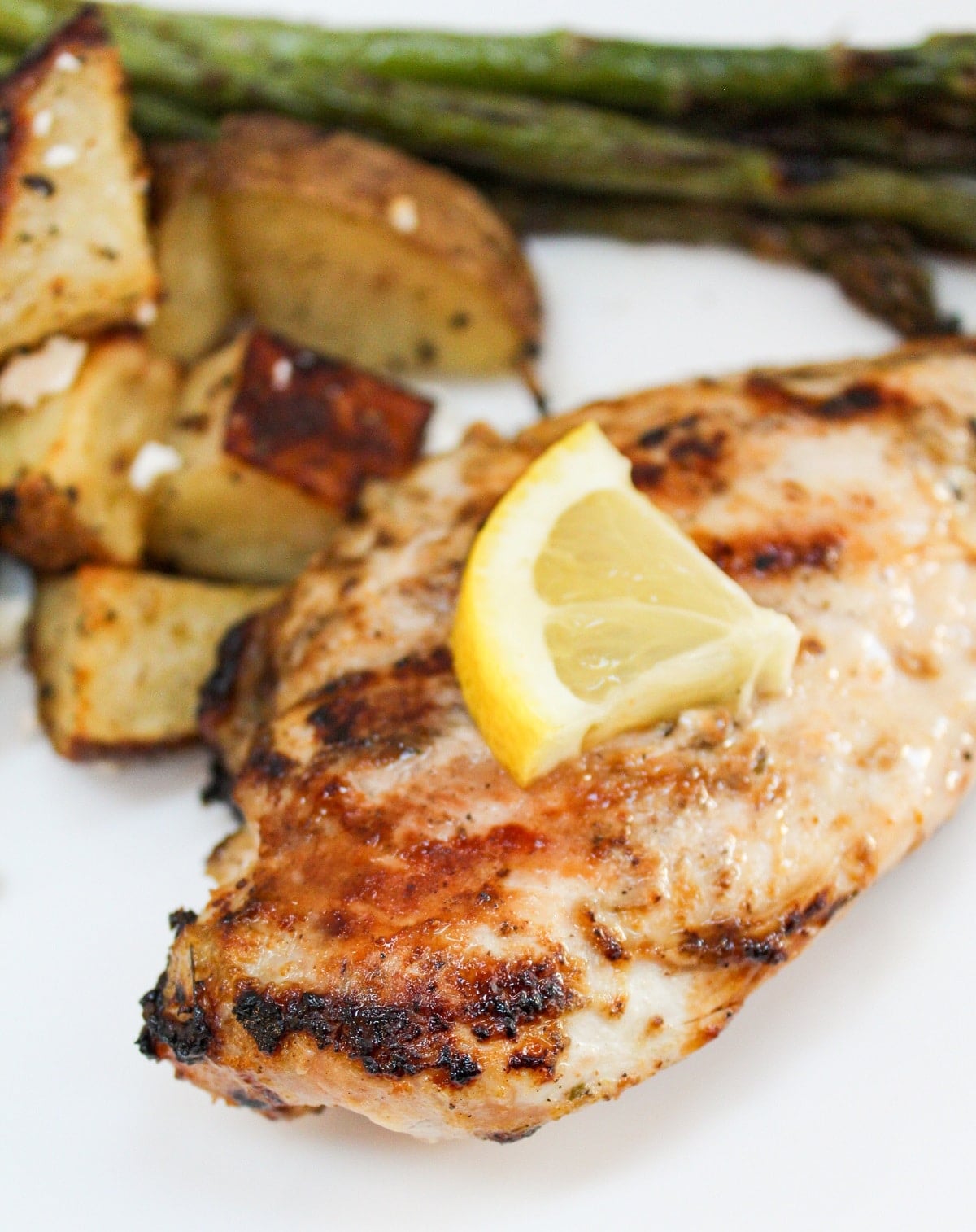 grilled lemon pepper chicken on white plate with sliced lemon