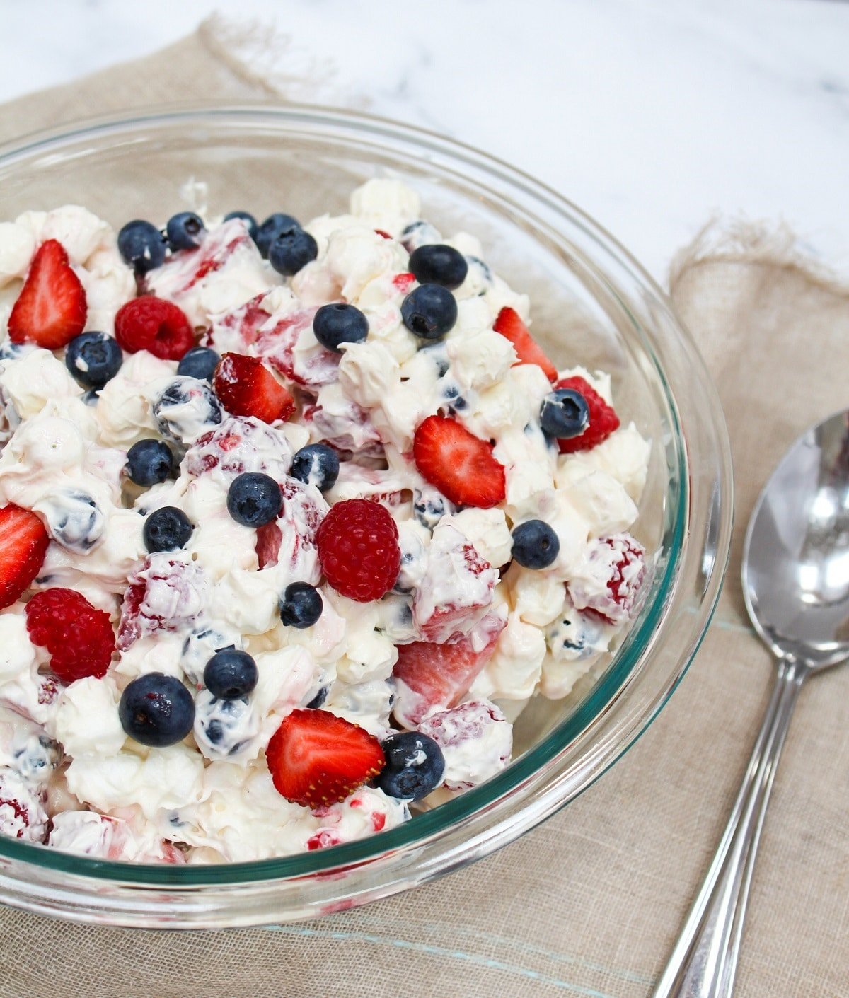 red white and blue cheesecake salad in a bowl with a spoon next to it