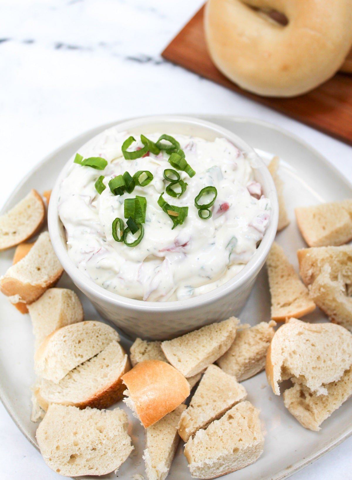 bagel dip in a white dish with bagel pieces on the side