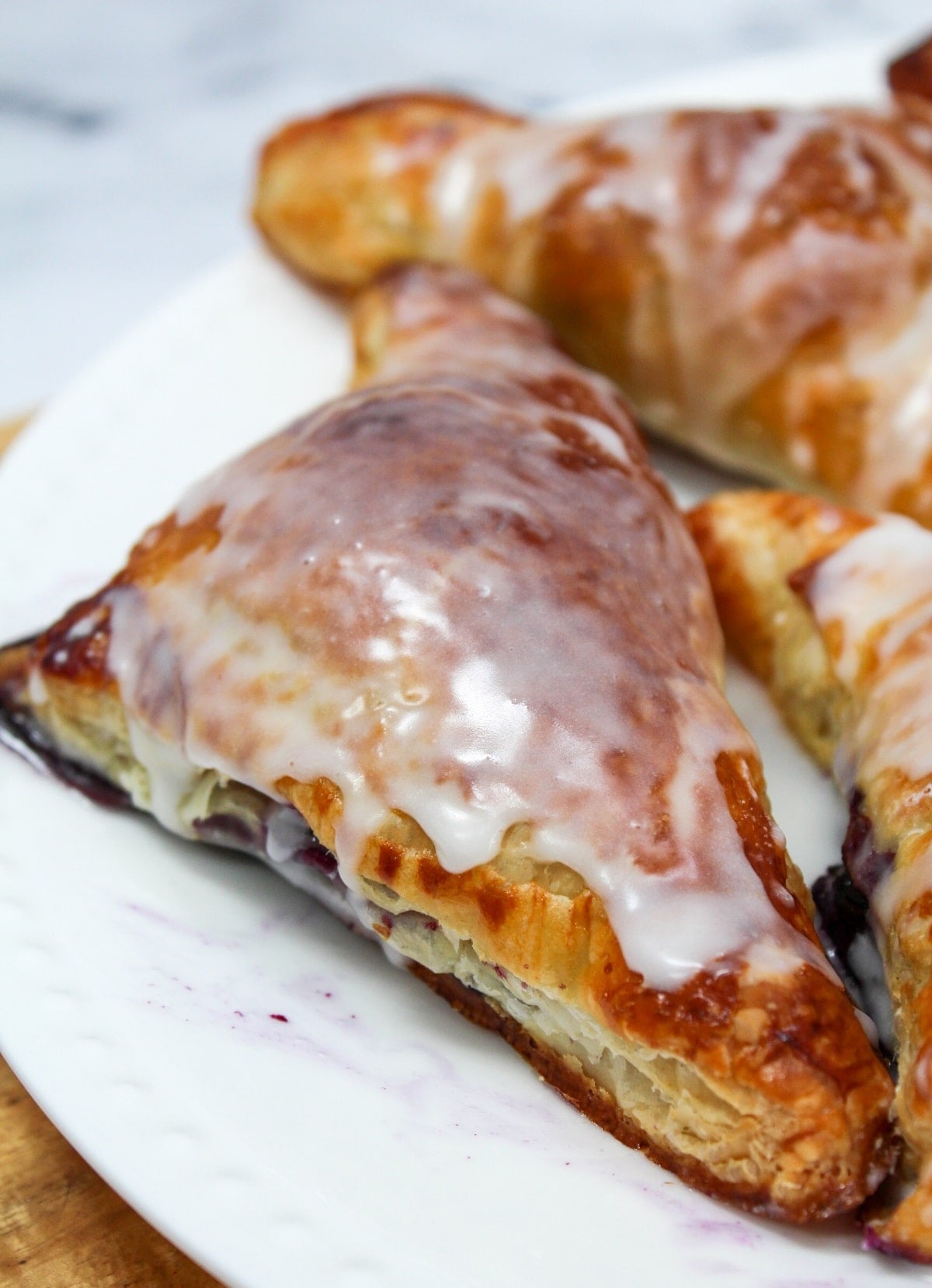 cooked blueberry turnover with frosting on a white plate