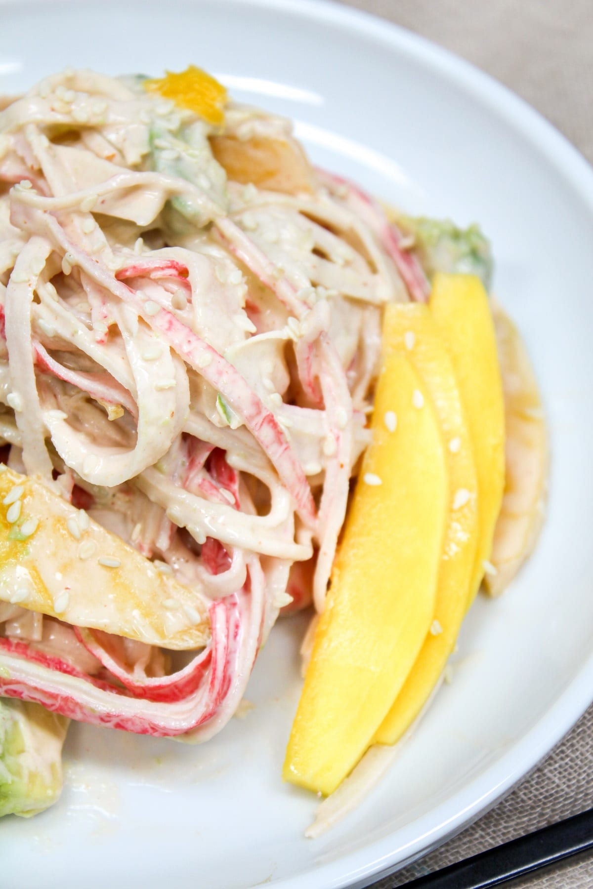 spicy kani salad on a plate with mango slices