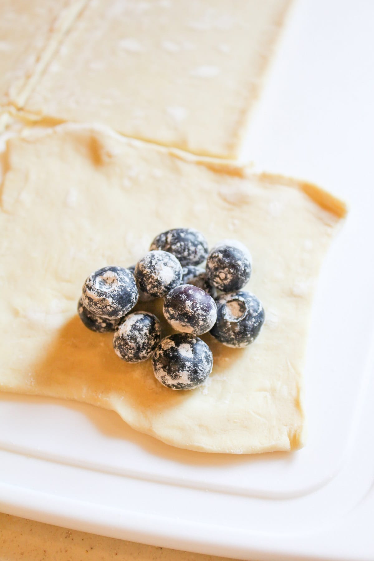 blueberries rolled in cornstarch and sugar on a square of puff pastry