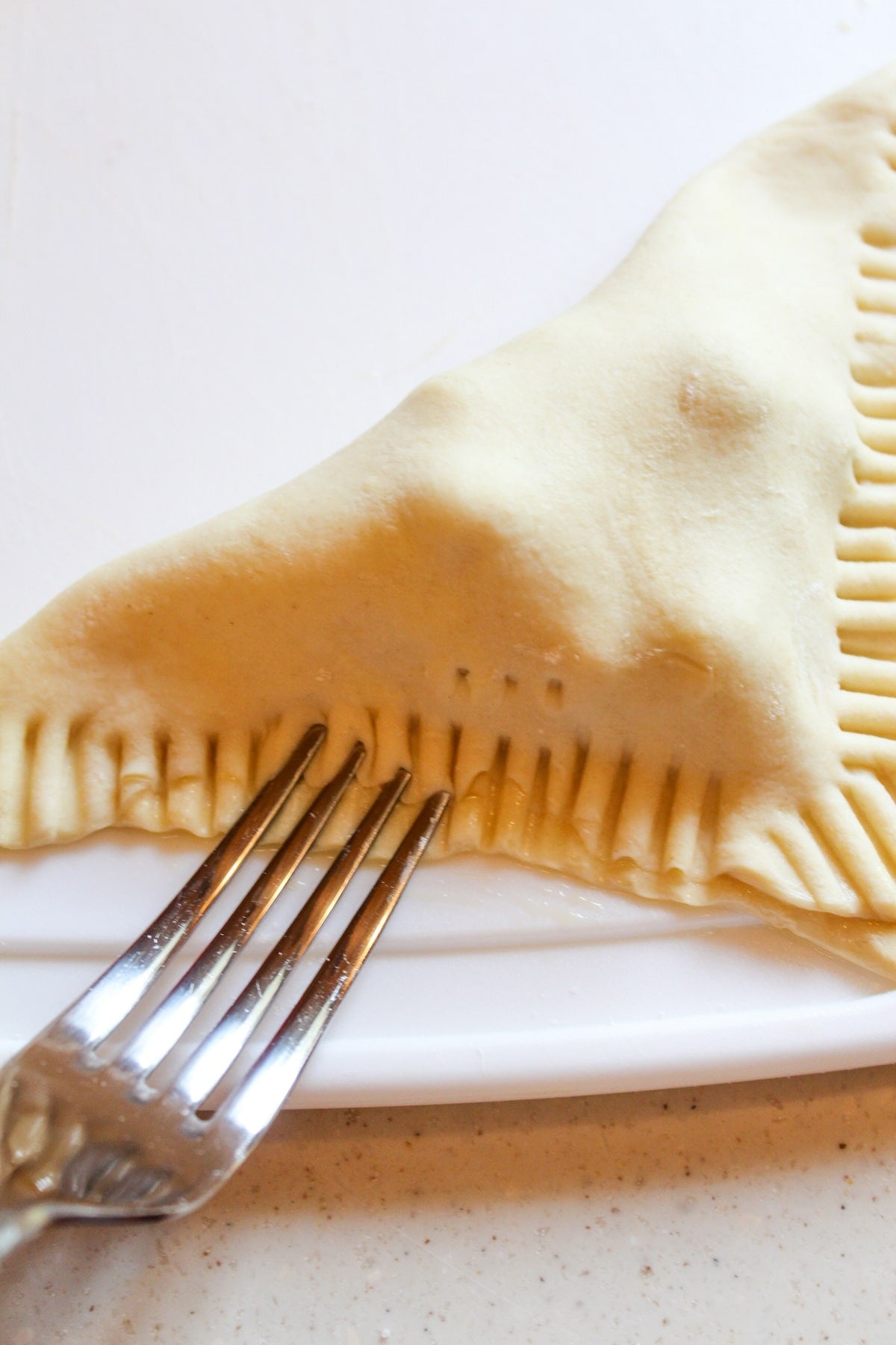 sealing edges of dough with a fork