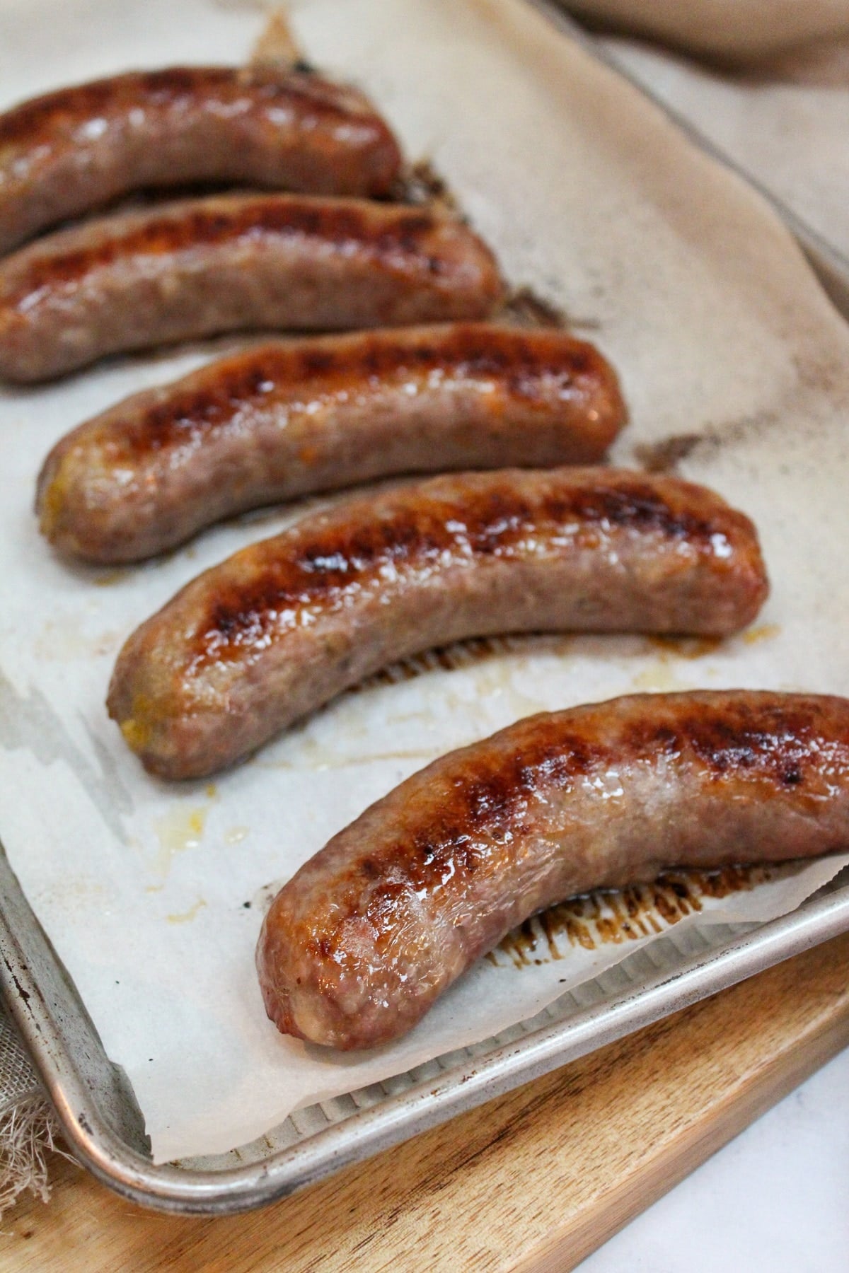 oven baked brats on a baking sheet
