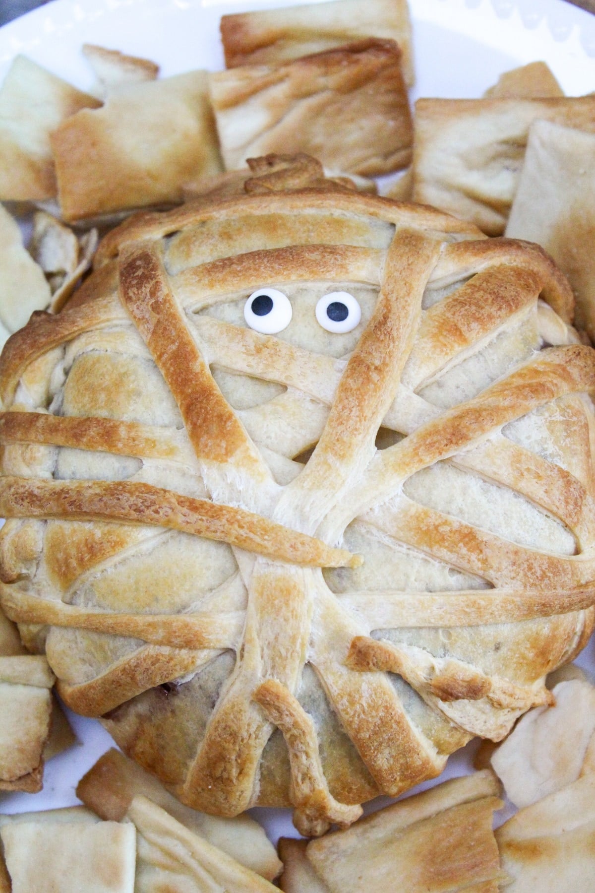 mummy wrapped brie on a plate with crackers