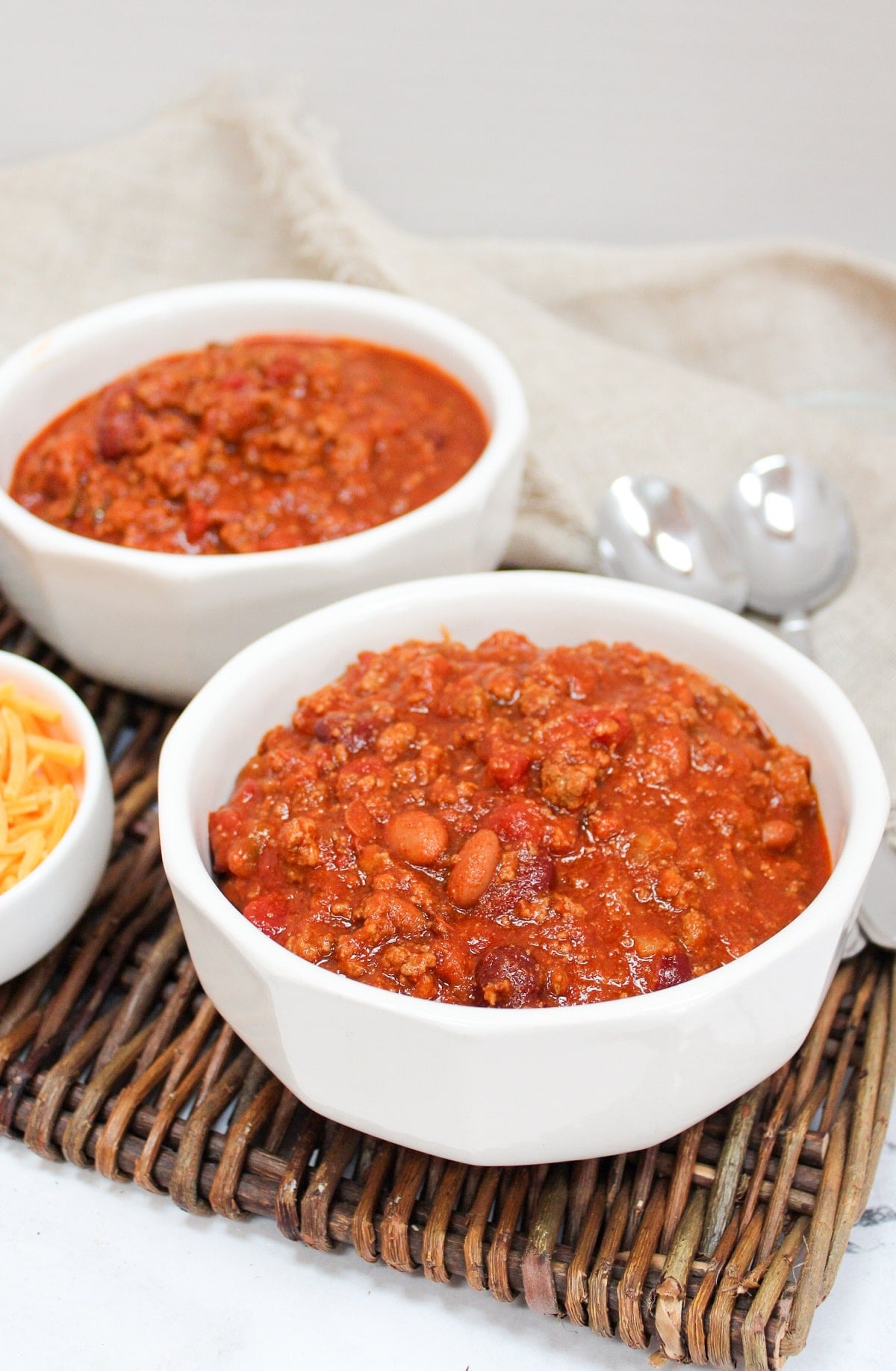 venison chili in bowl with cheese on the side