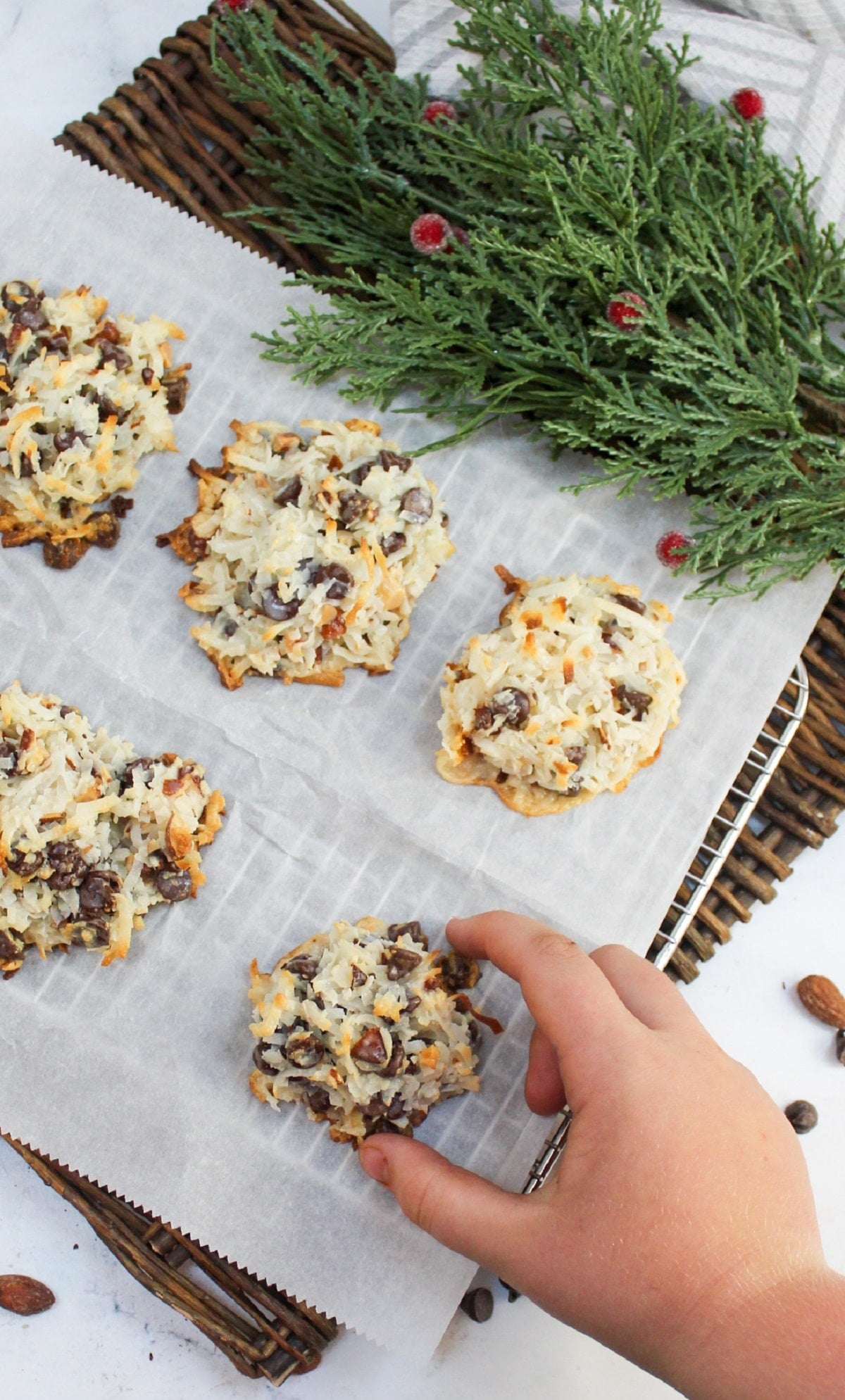 almond joy cookie on baking sheet with child's hand grabbing a cookie