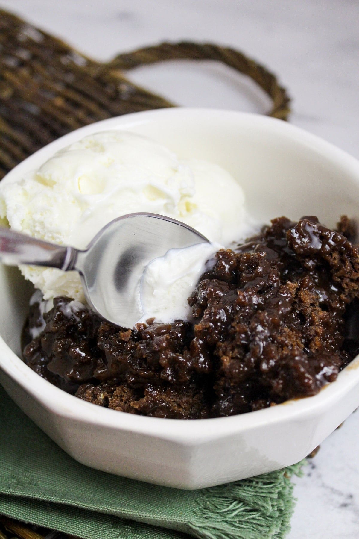 slow cooker chocolate cobbler in a bowl with vanilla ice cream with spoon