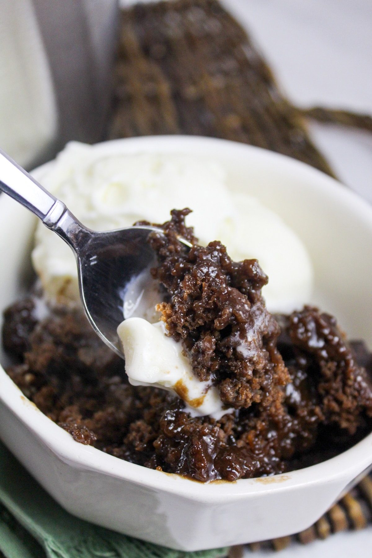 slow cooker chocolate cobbler in a bowl with vanilla ice cream with spoon