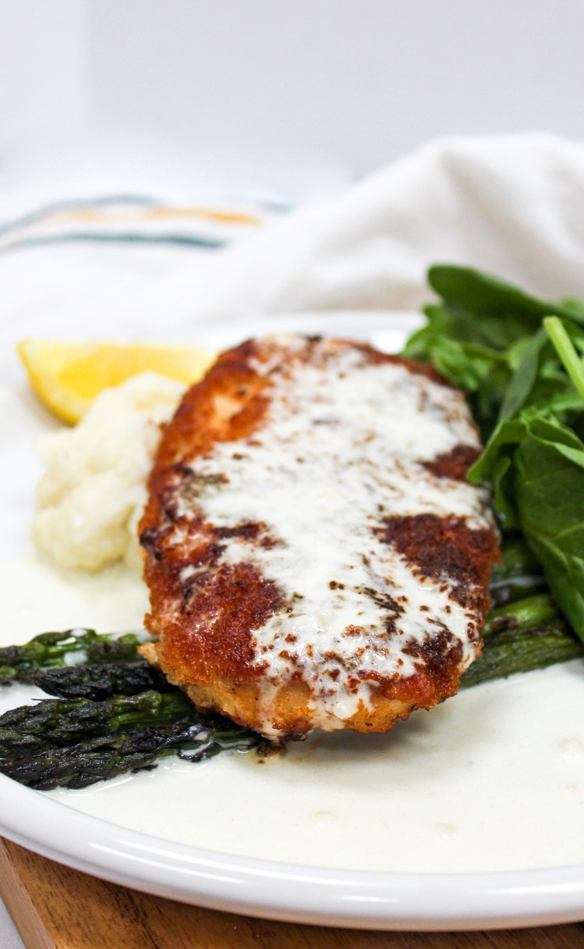chicken costoletta on a plate with lemon sauce and asparagus.