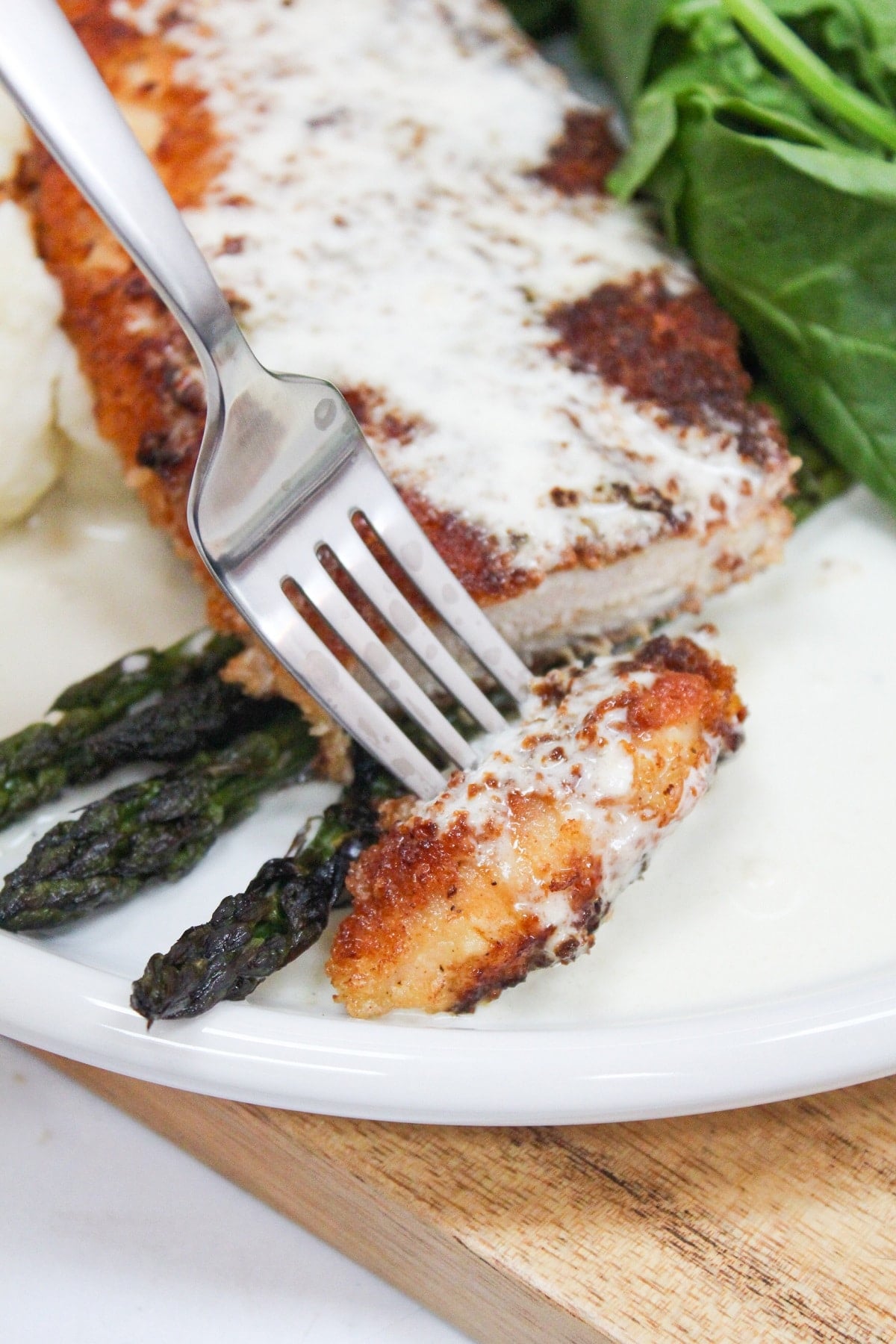 chicken costoletta on a plate with lemon sauce and asparagus.