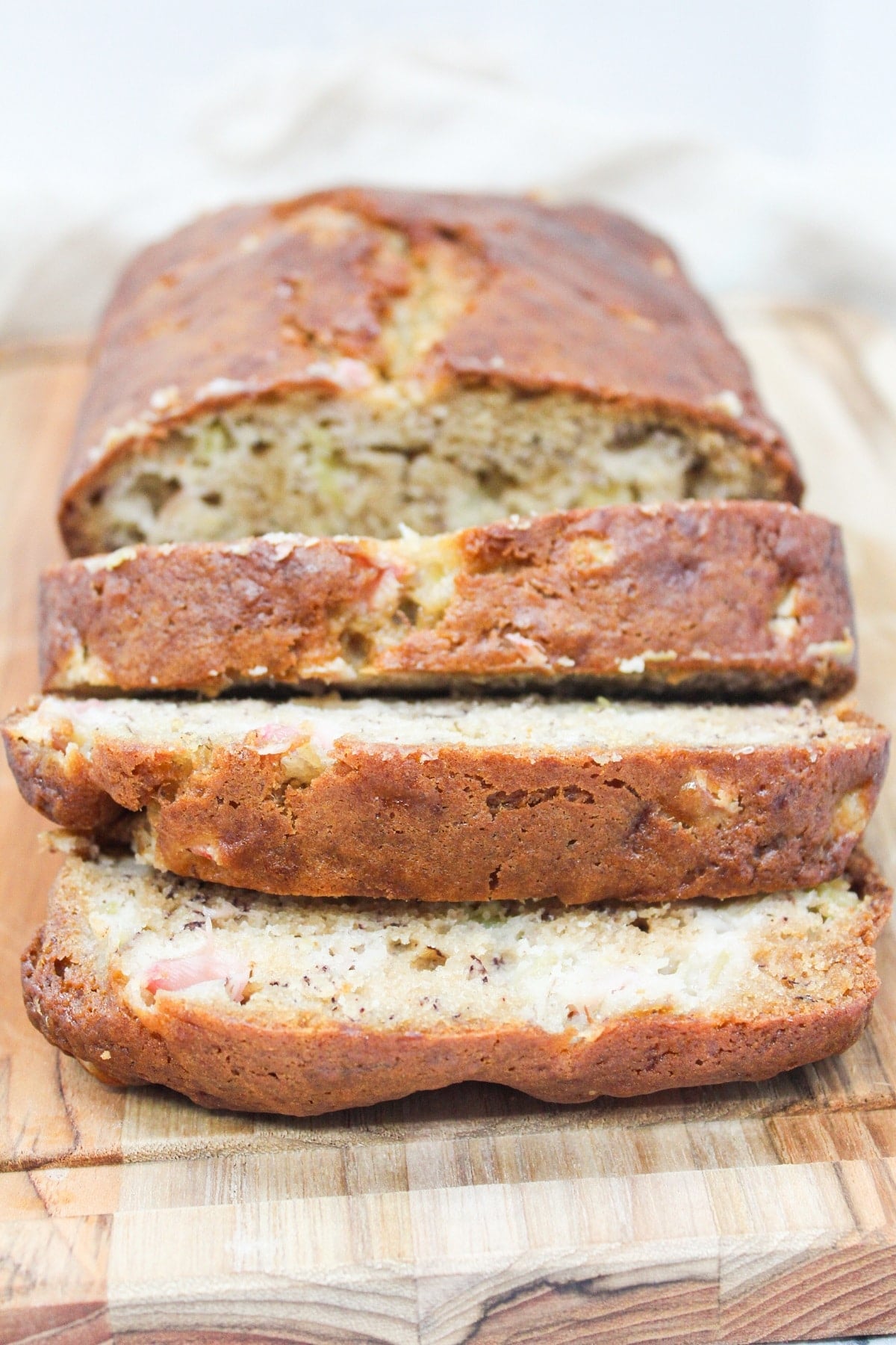 Sliced Rhubarb Banana bread on a wooden cutting board.