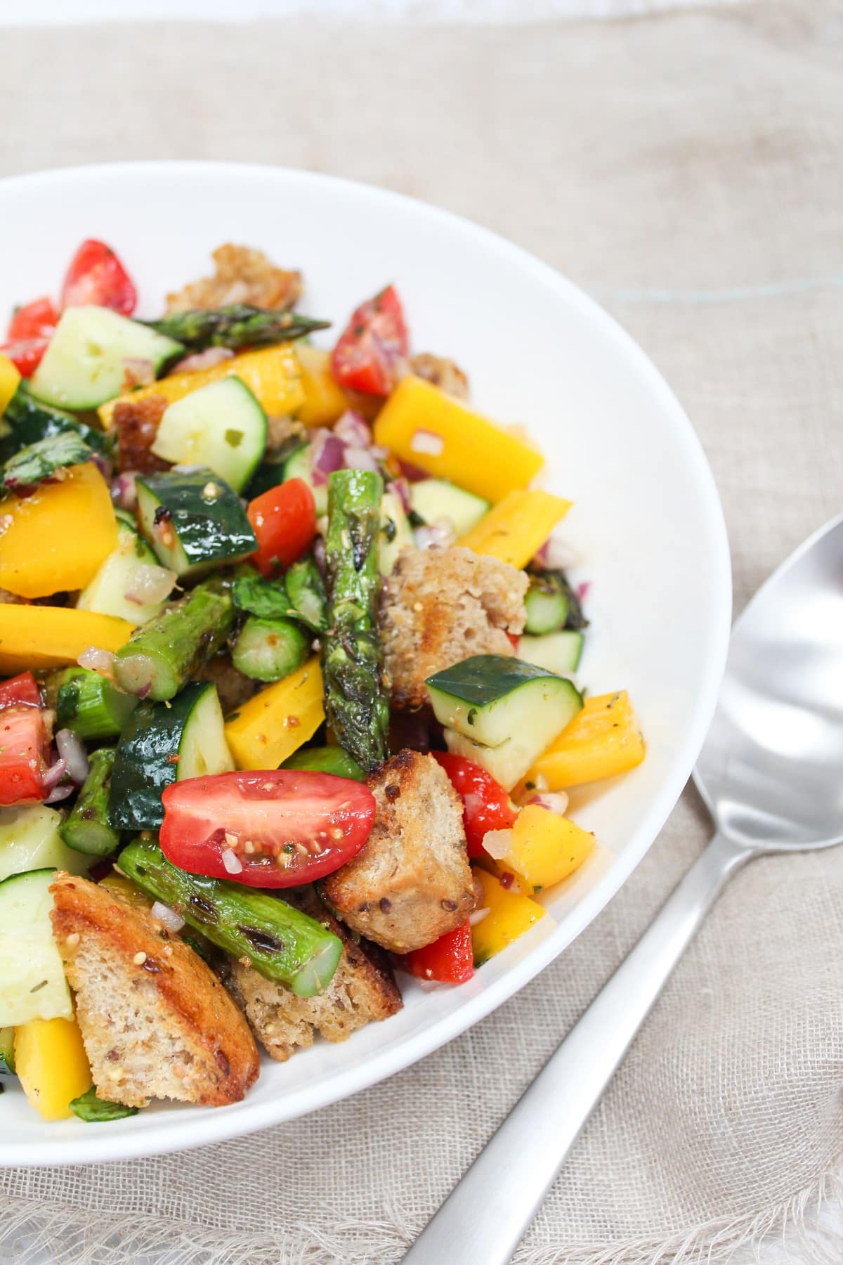 asparagus panzanella salad in a white bowl.
