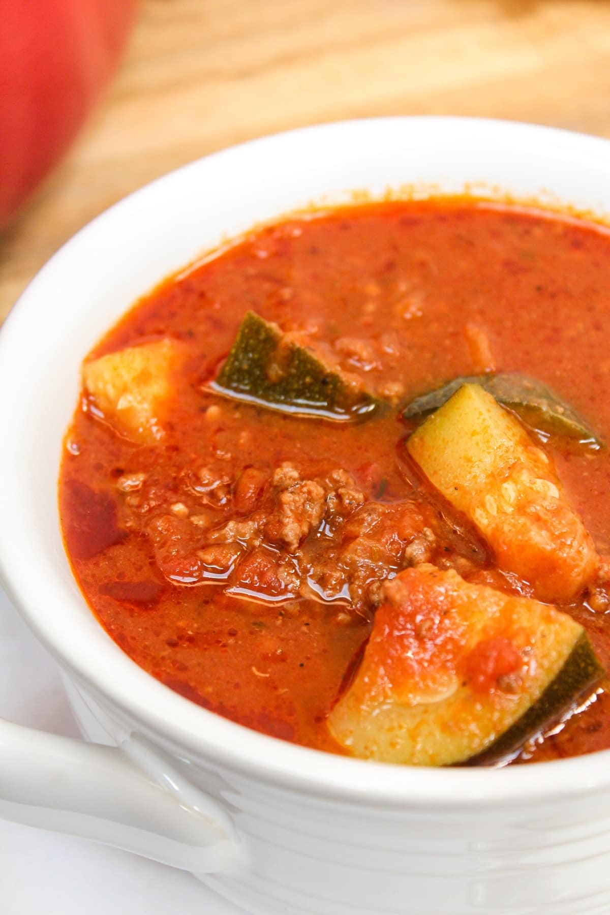 zucchini and hamburger stew in a white bowl.