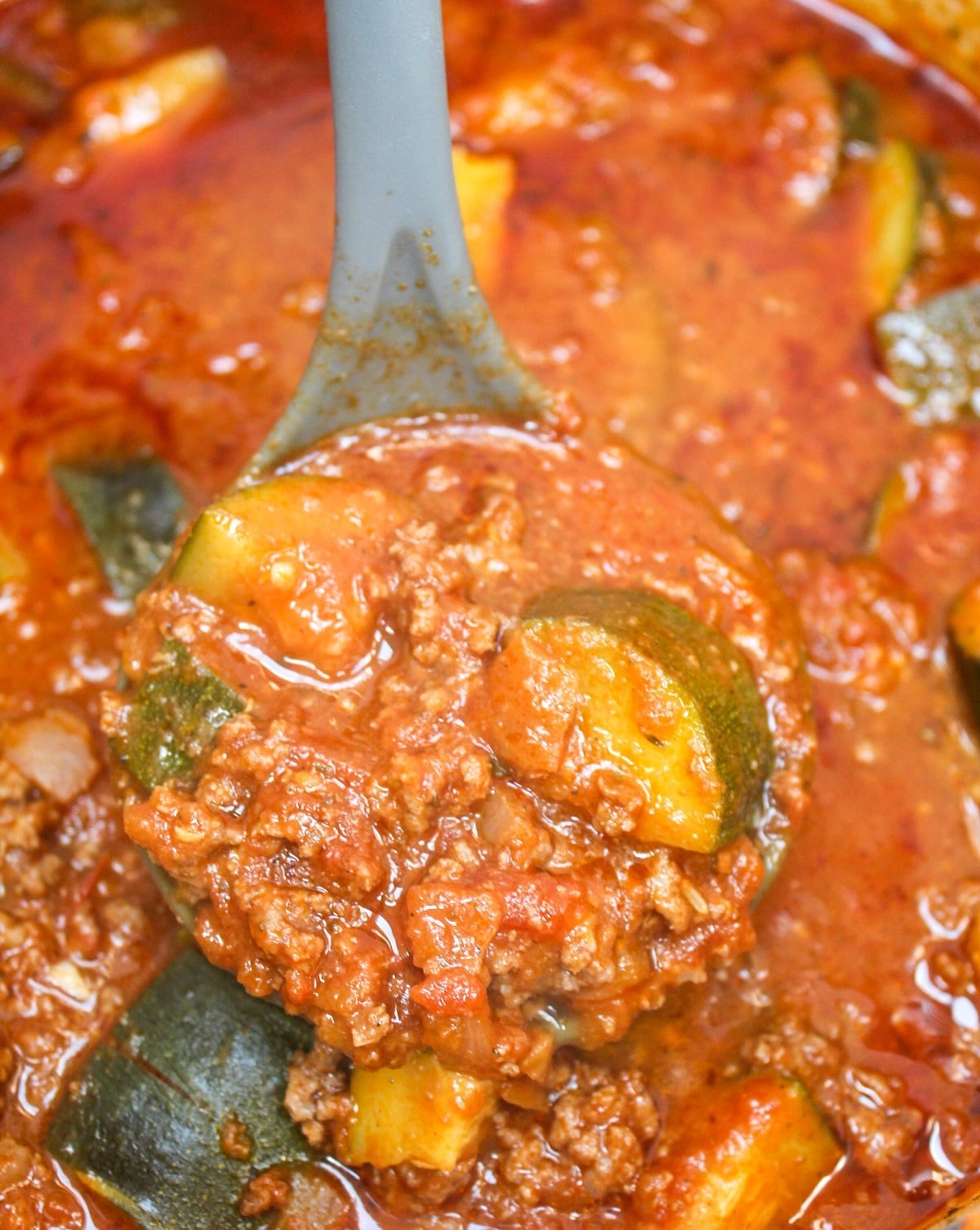 zucchini and hamburger stew ladled from a stew pot.