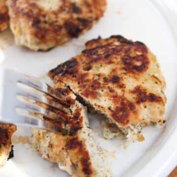 chicken formed into sausage patties. Cooked in a skillet till golden brown and served on a white plate and cut with a fork.