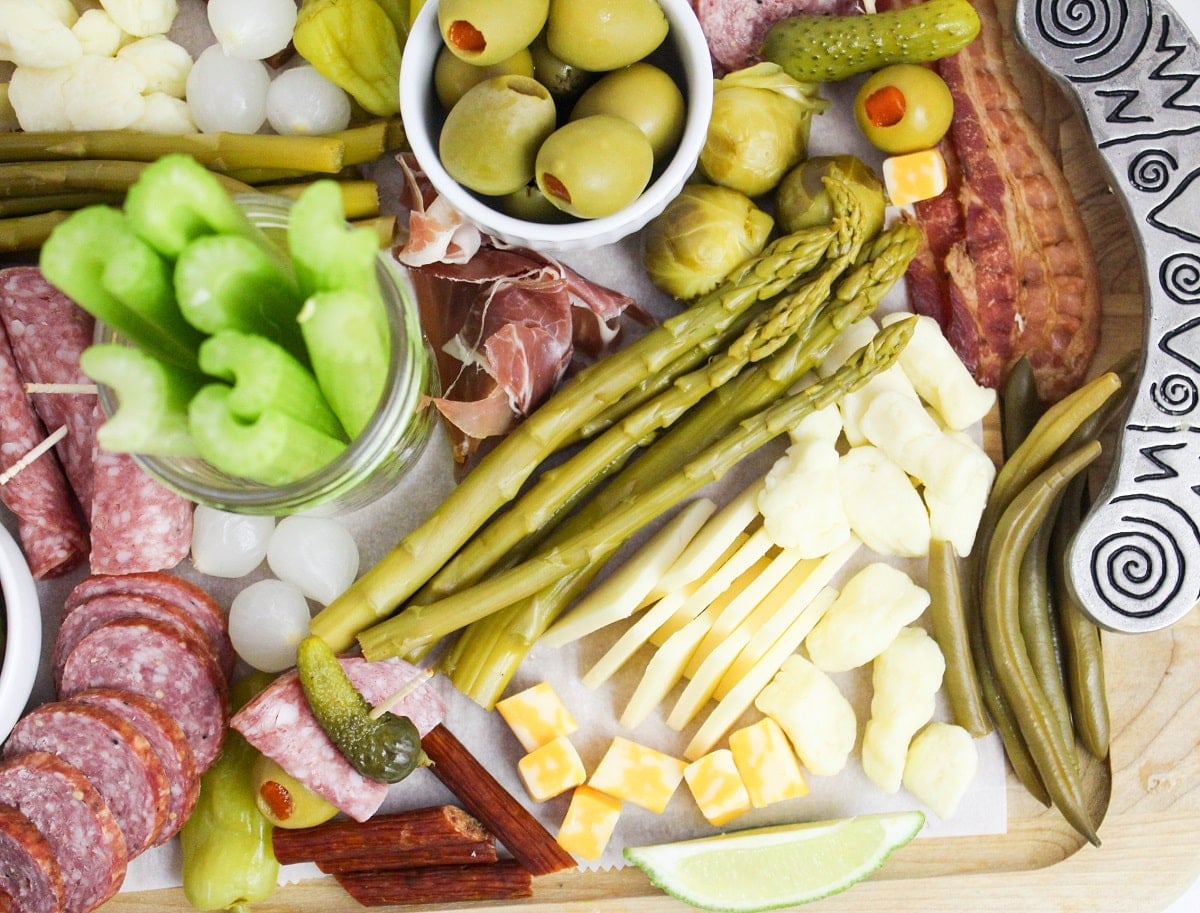 Overhead view of a completed board. The toppings are a variety of meats, cheeses, pickles, olives, pepper, vegetables.